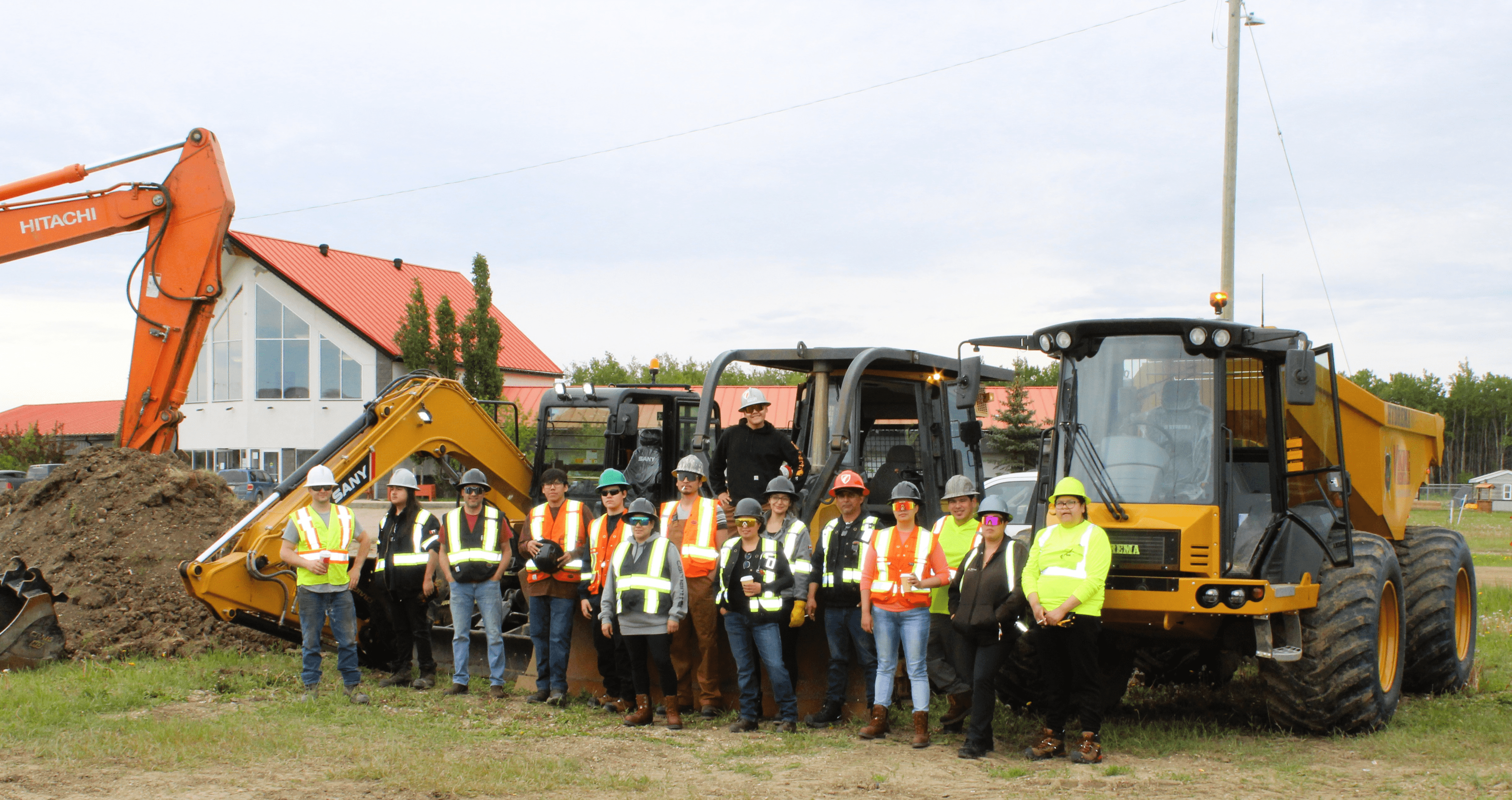 Group of workers in safety gear posing with construction equipment.