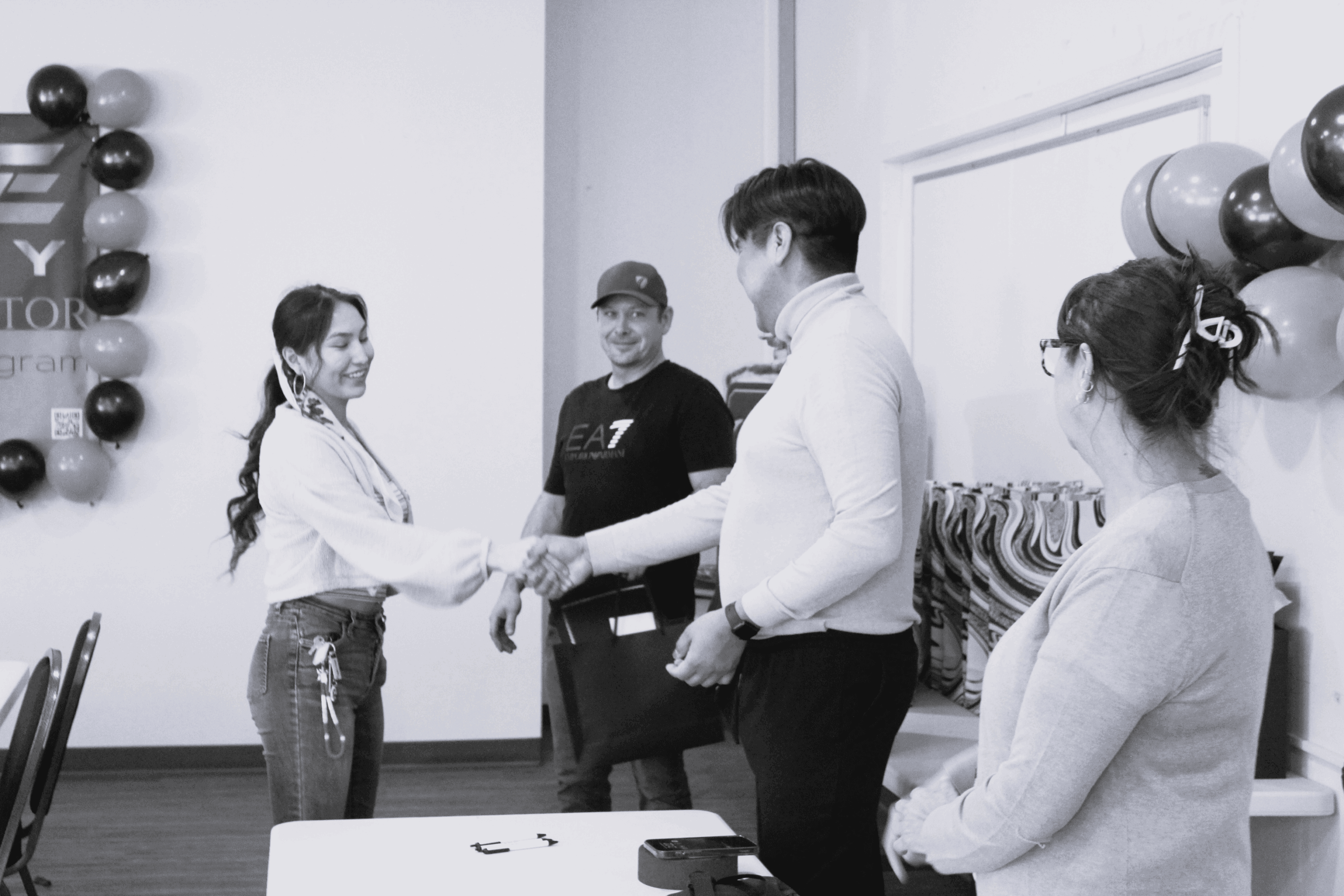 Two people shaking hands while others watch in a casual meeting.